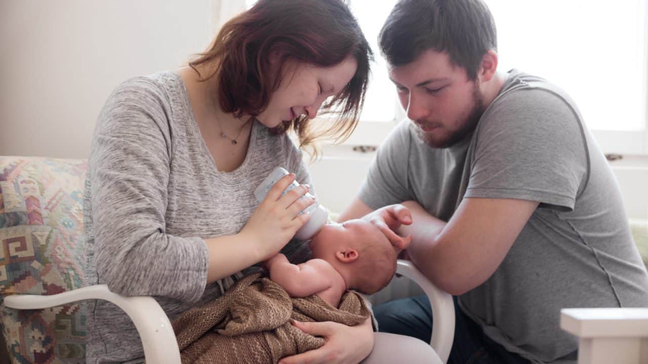 mother feeding newborn while father looks