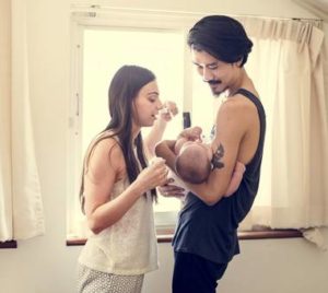 father holds baby while standing with mother