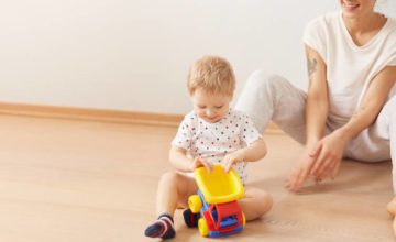 baby and mom play with toy truck on floor