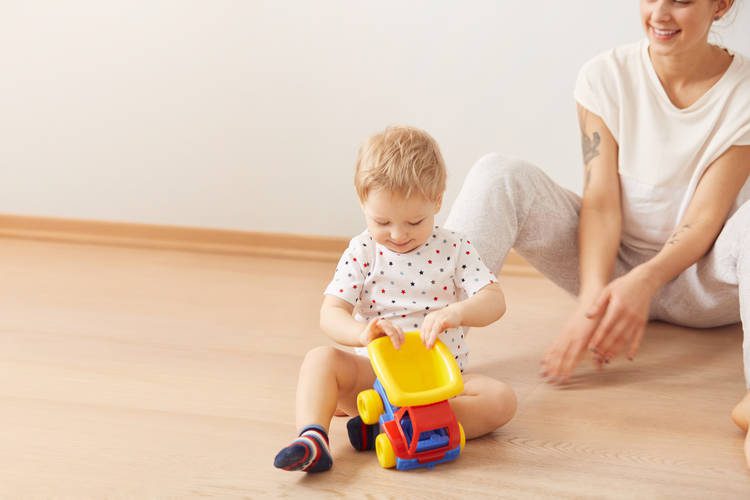 baby and mom play with toy truck on floor