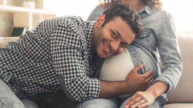 dad hugging mom's pregnant stomach