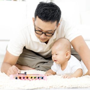 A man shows a baby how to play a toy xylophone.