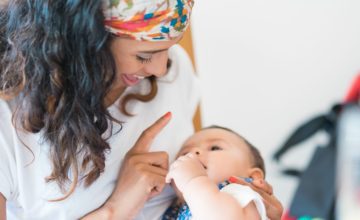 A mother holds her child and boops them on the nose.