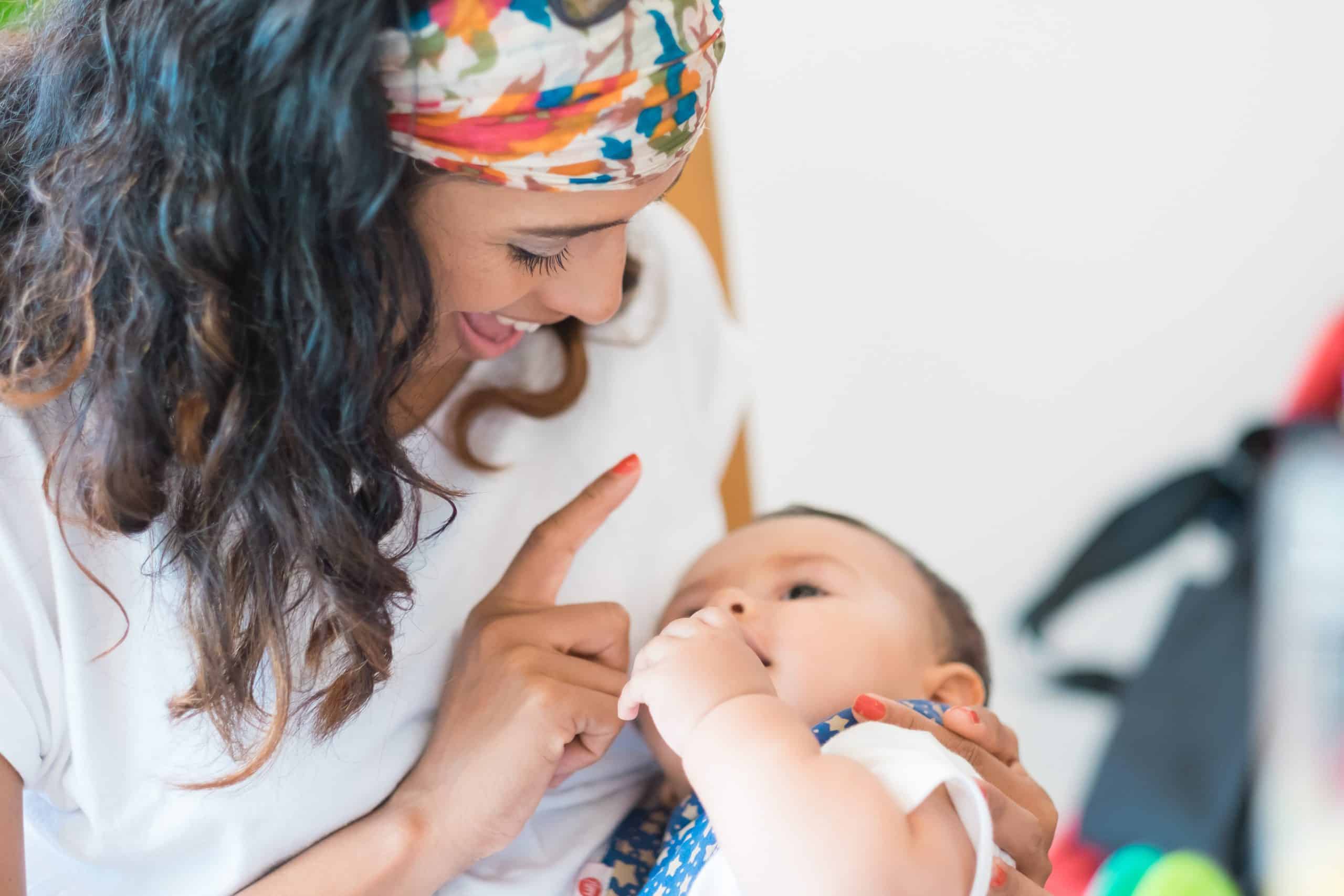 A mother holds her child and boops them on the nose.