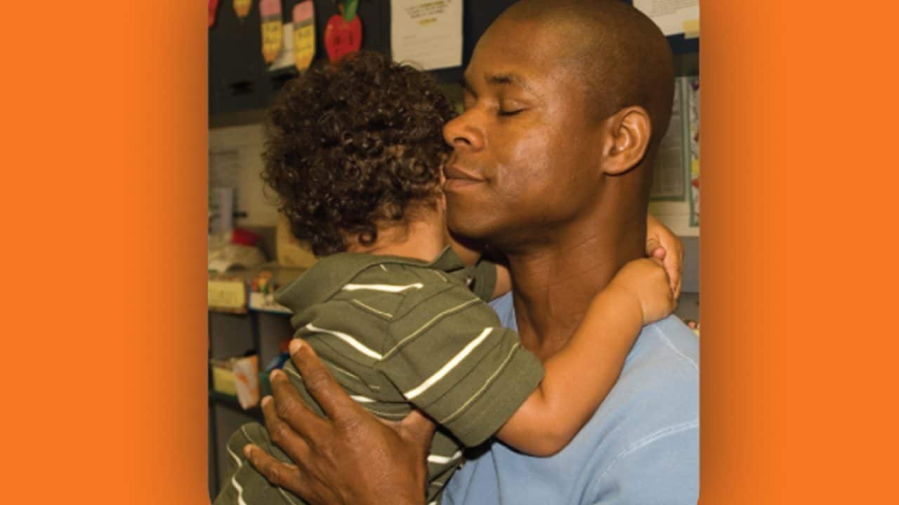 Father eyes closed hugging son in arms