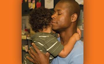 Father eyes closed hugging son in arms