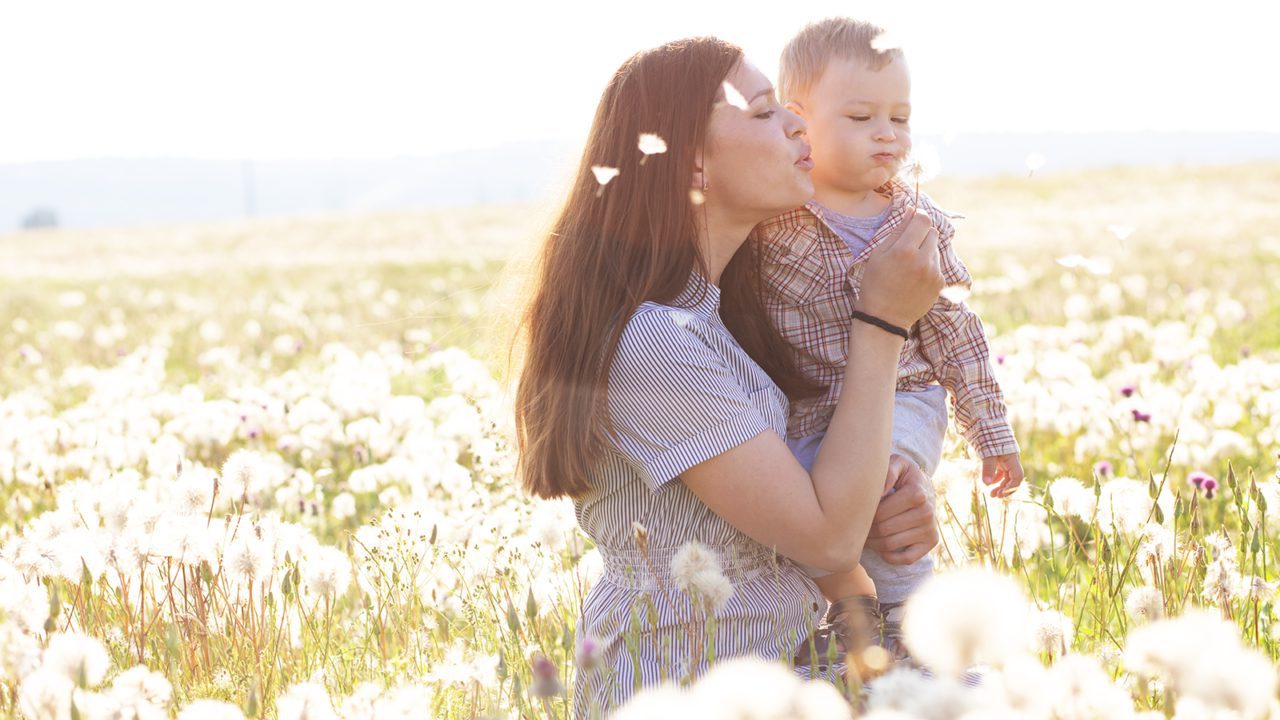 woman and child flowing dandelions in field