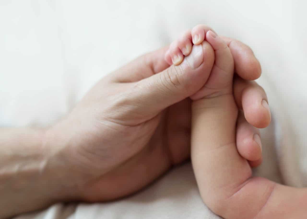 Parent holding infant's hand