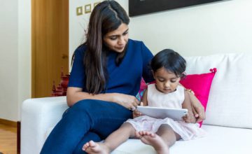 Mother Helping Child Hold a Tablet