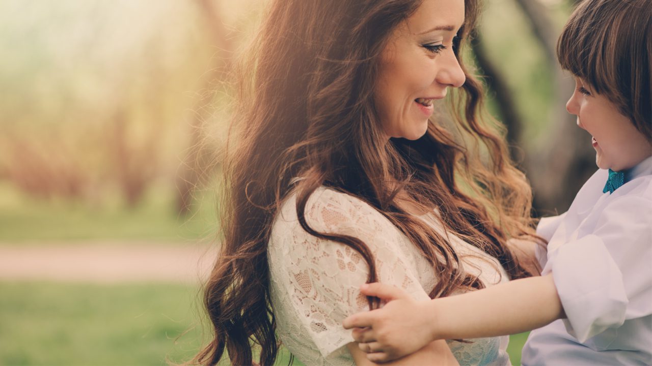 mother holds child in arms smiling face to face