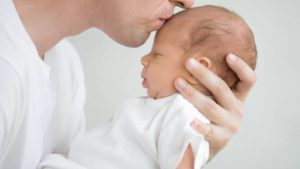 Dad kissing newborn on forehead