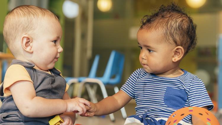 Infants holding hands in a childcare classroom