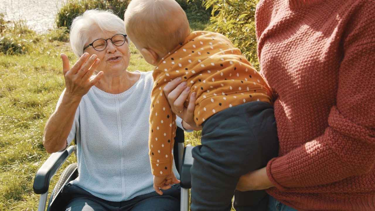 grandparent reaches for baby held in parent arms