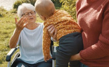 grandparent reaches for baby held in parent arms