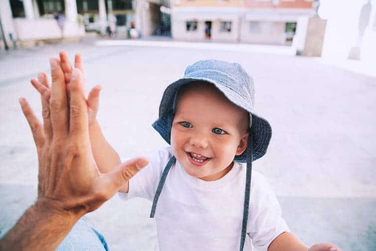 Toddler boy high fiving adult