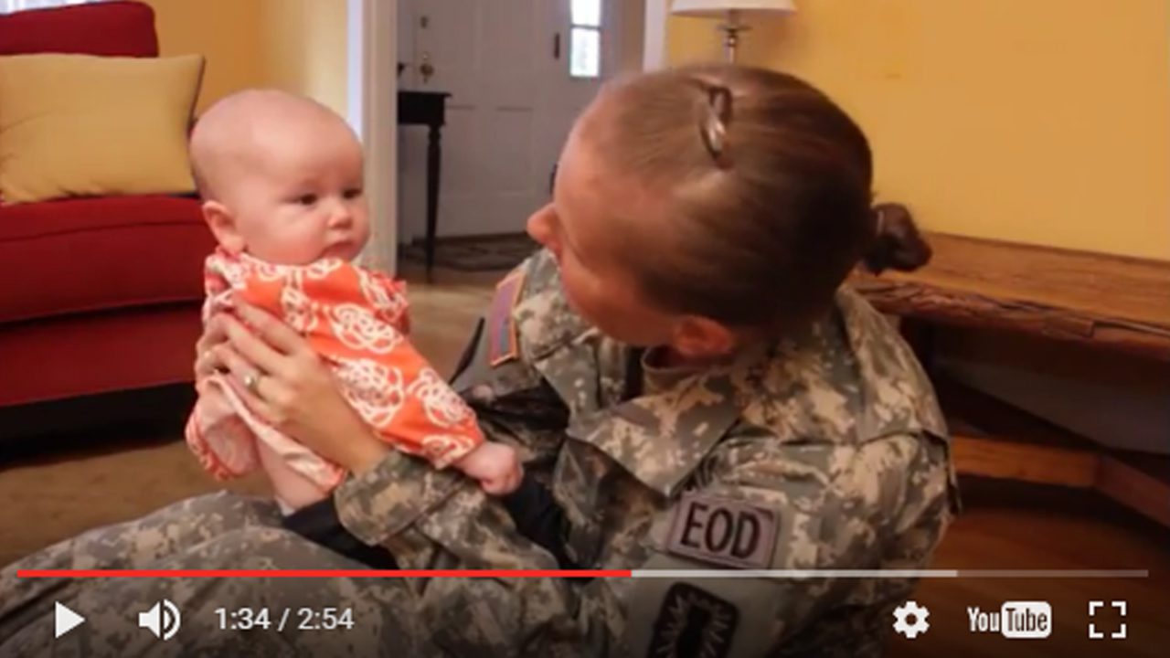 video still of woman in military uniform smiling at baby