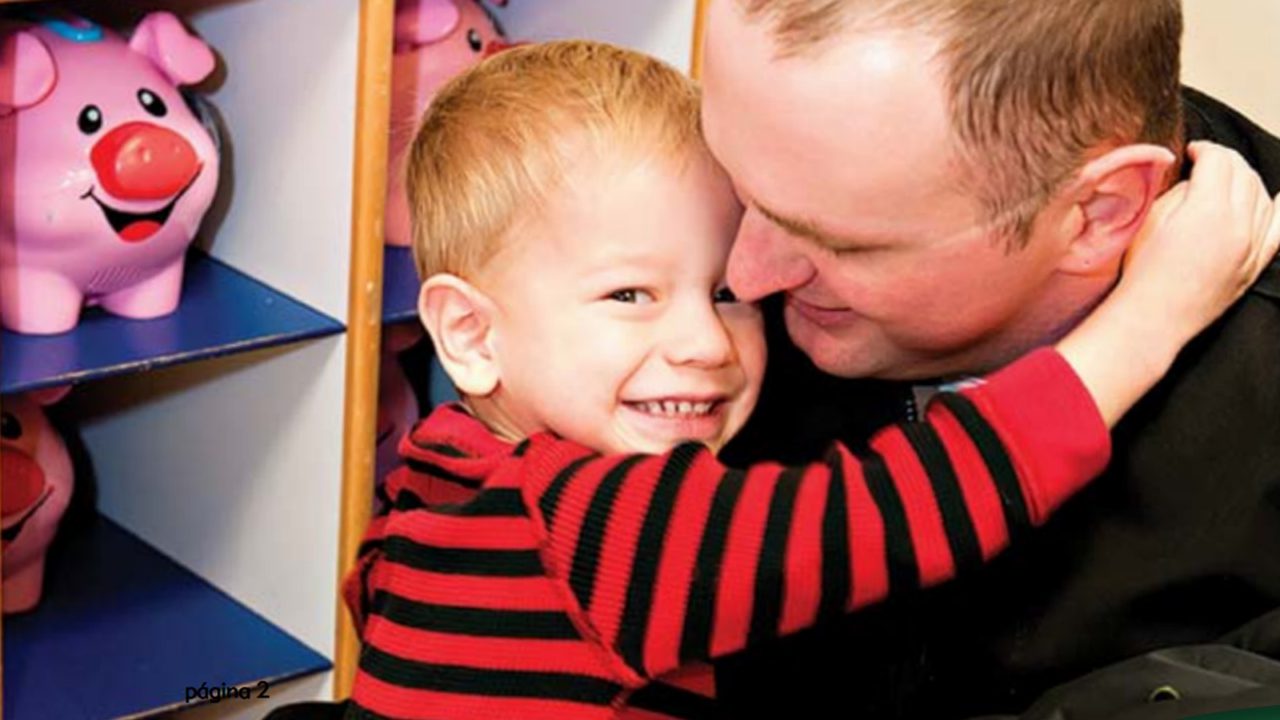 man holds young boy looking down at him while he smiles with big grin