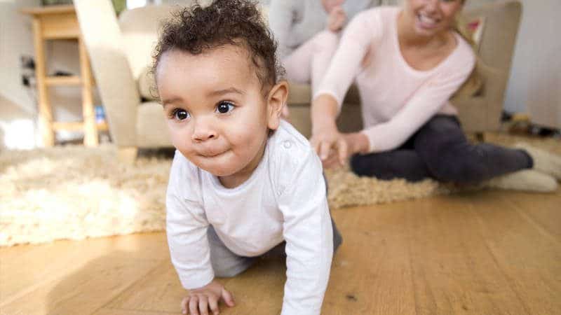 Infant Learning to Crawl with Mother in Background