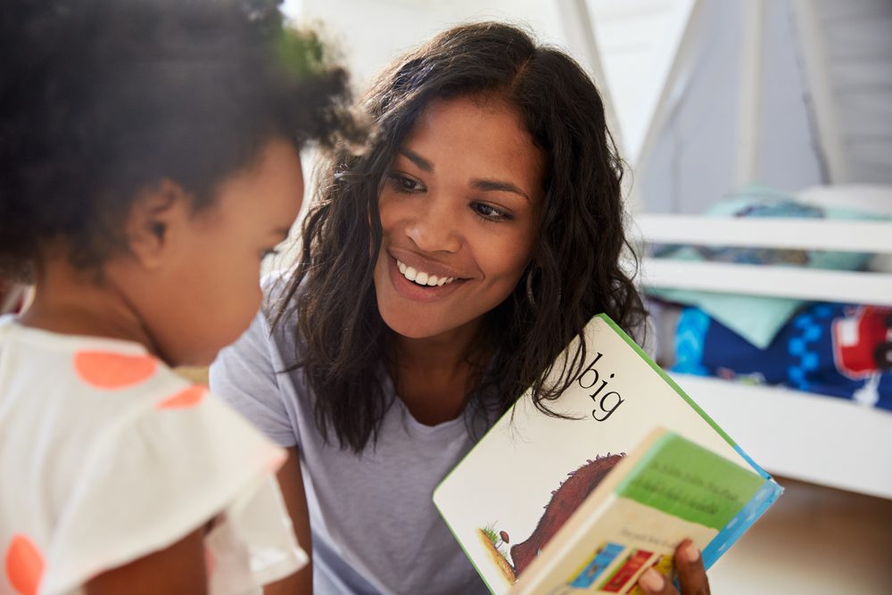 A mother shows a picture book to her toddler.