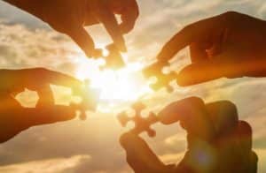 Four hands holding puzzle pieces