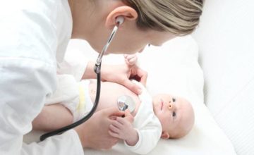 Pediatrician using a stethoscope checking on a baby
