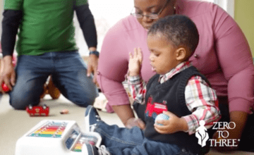 Early childhood educator watching toddler playing toy xylophone