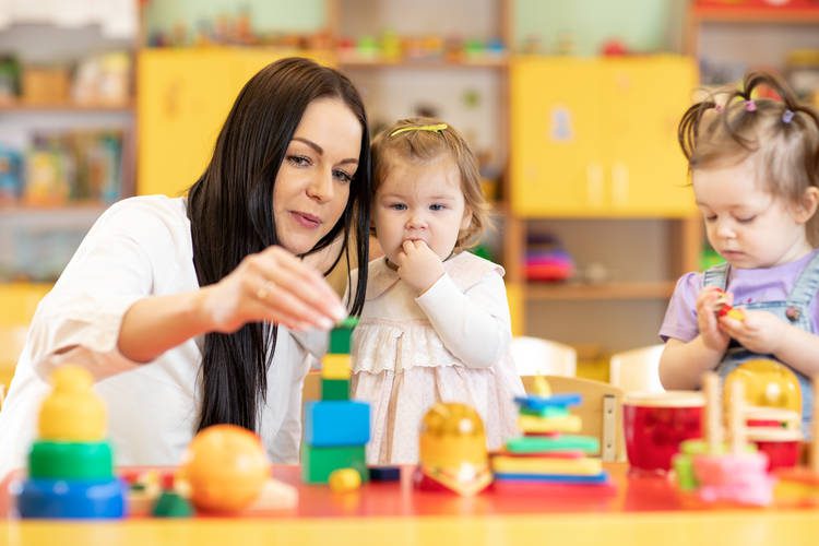 Parent with two toddlers playing with toys at child care