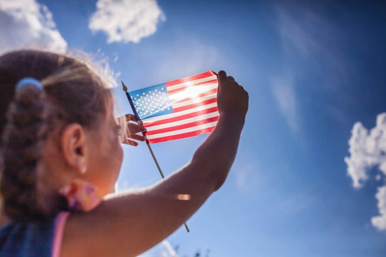 Child holding American flag to the sun