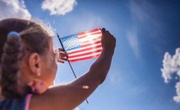 Child holding American flag to the sun