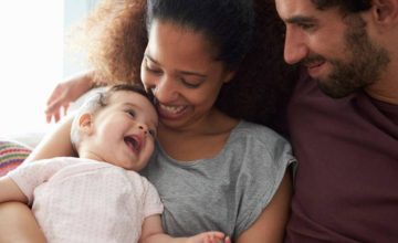 Parents smiling holding a baby laughing