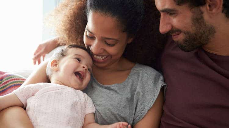 Parents smiling holding a baby laughing