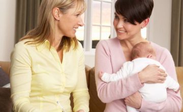 Mother with their baby smiling with home visiting professional