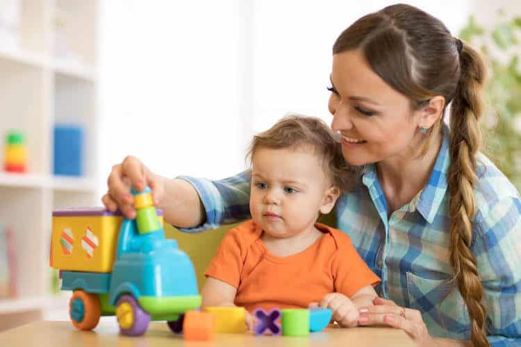 Parent playing with baby and a toy truck