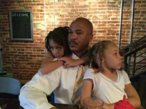 man sitting with two daughters