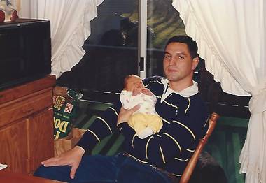 father in rocking chair holding newborn