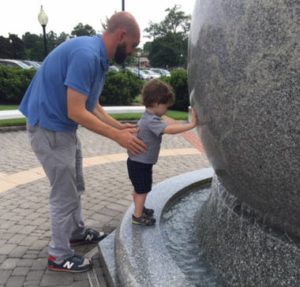 father standing with son touching statue