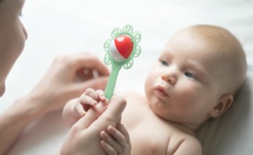 A baby looks at a rattle.