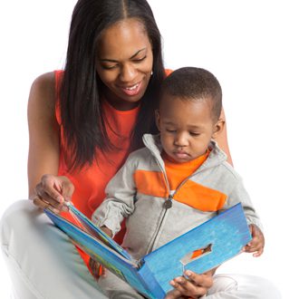 A mother holds her toddler in her lap while she reads to him.