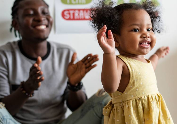 Happy parent clapping while toddler learning to walk