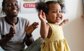 Father clapping while baby girl walks