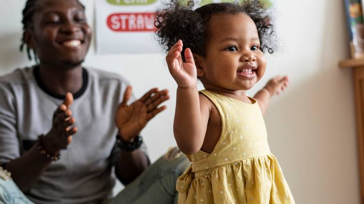 Father clapping while baby girl walks