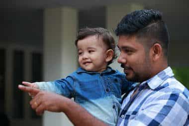 Father holding son and both are pointing to the left