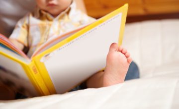 A young child holds a book in their lap.