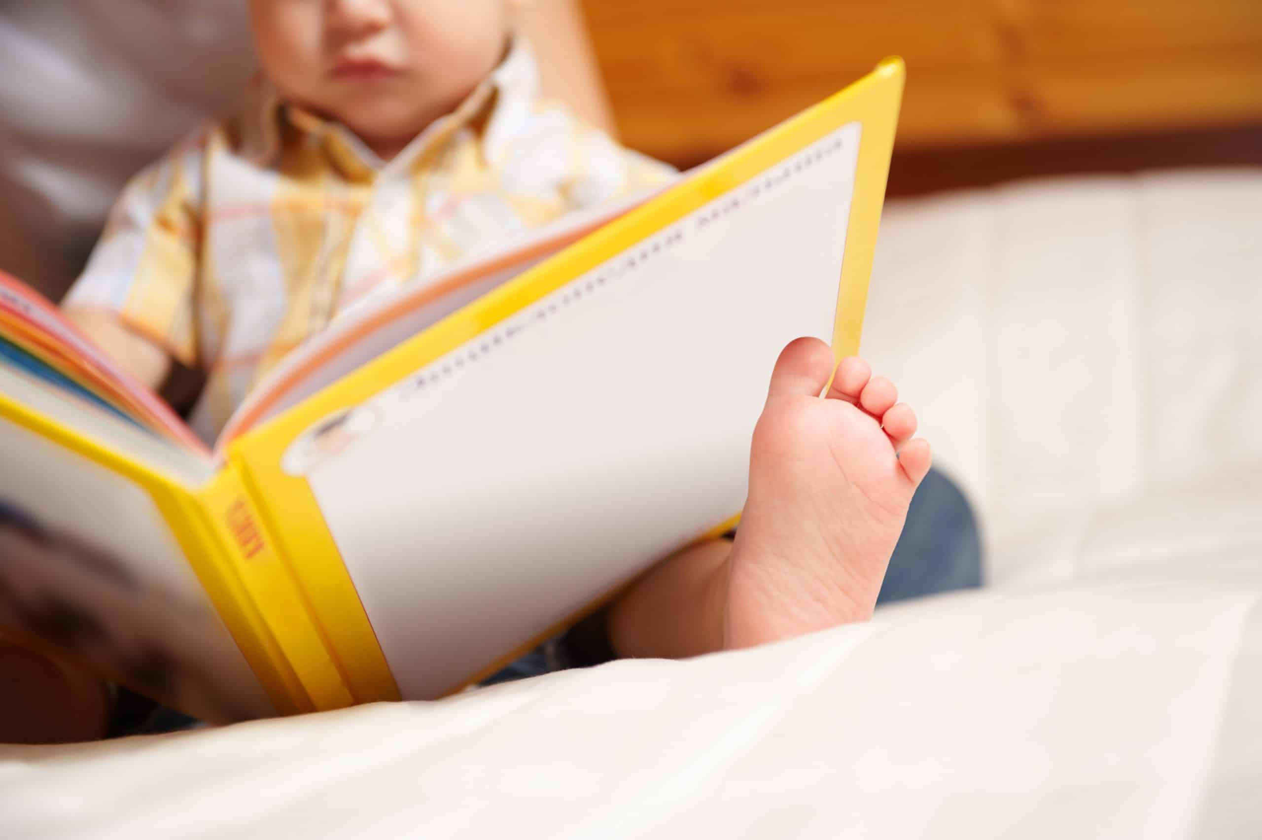 A young child holds a book in their lap.