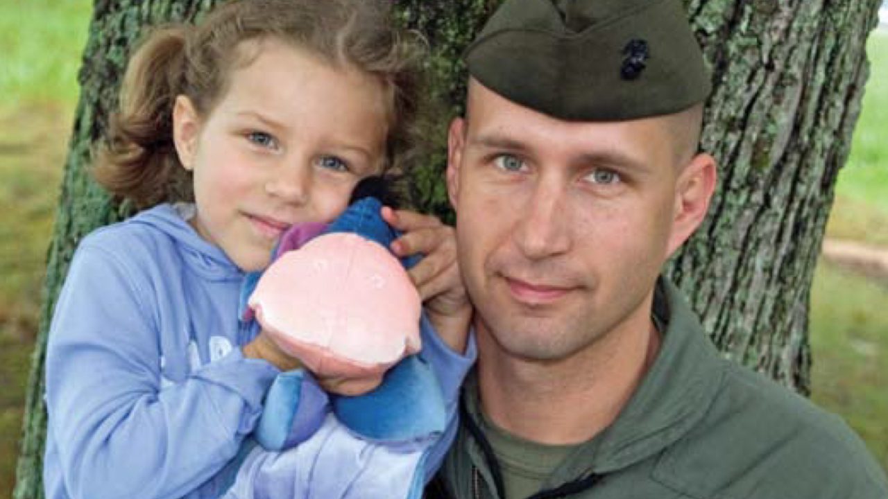 military father with young daughter holding toy smiling at camera