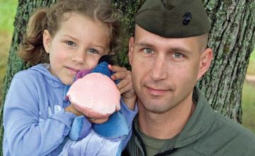 military father with young daughter holding toy smiling at camera