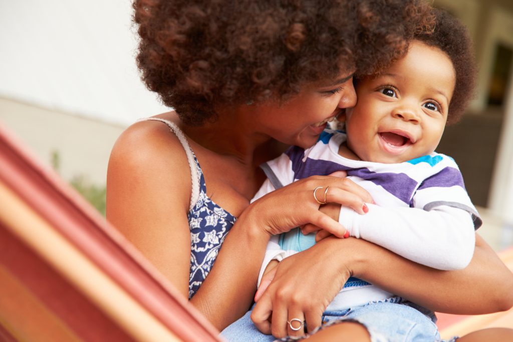 A mother smiles at and cuddles her baby.