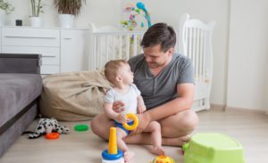 A father sits with his baby in their nursery.