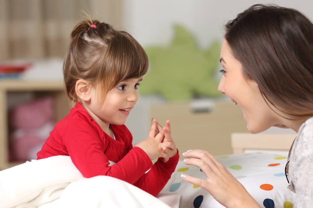 A mother and young child smile at each other.