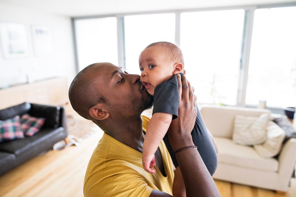 A father holds up and kisses his young baby.